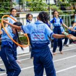 Group of schoolchildren enjoying outdoor games with hula hoops at a school event in Surat, India.