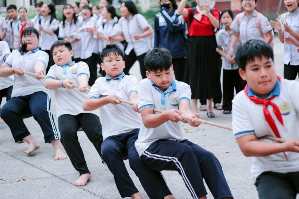 Group of school children energetically engaging in a tug-of-war game outdoors.