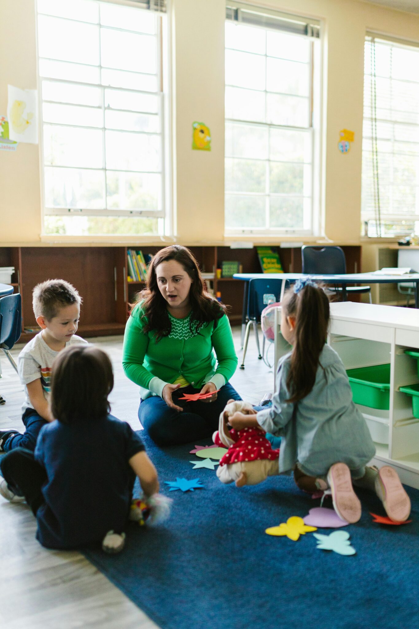 Teacher interacting with young children in a colorful kindergarten classroom.