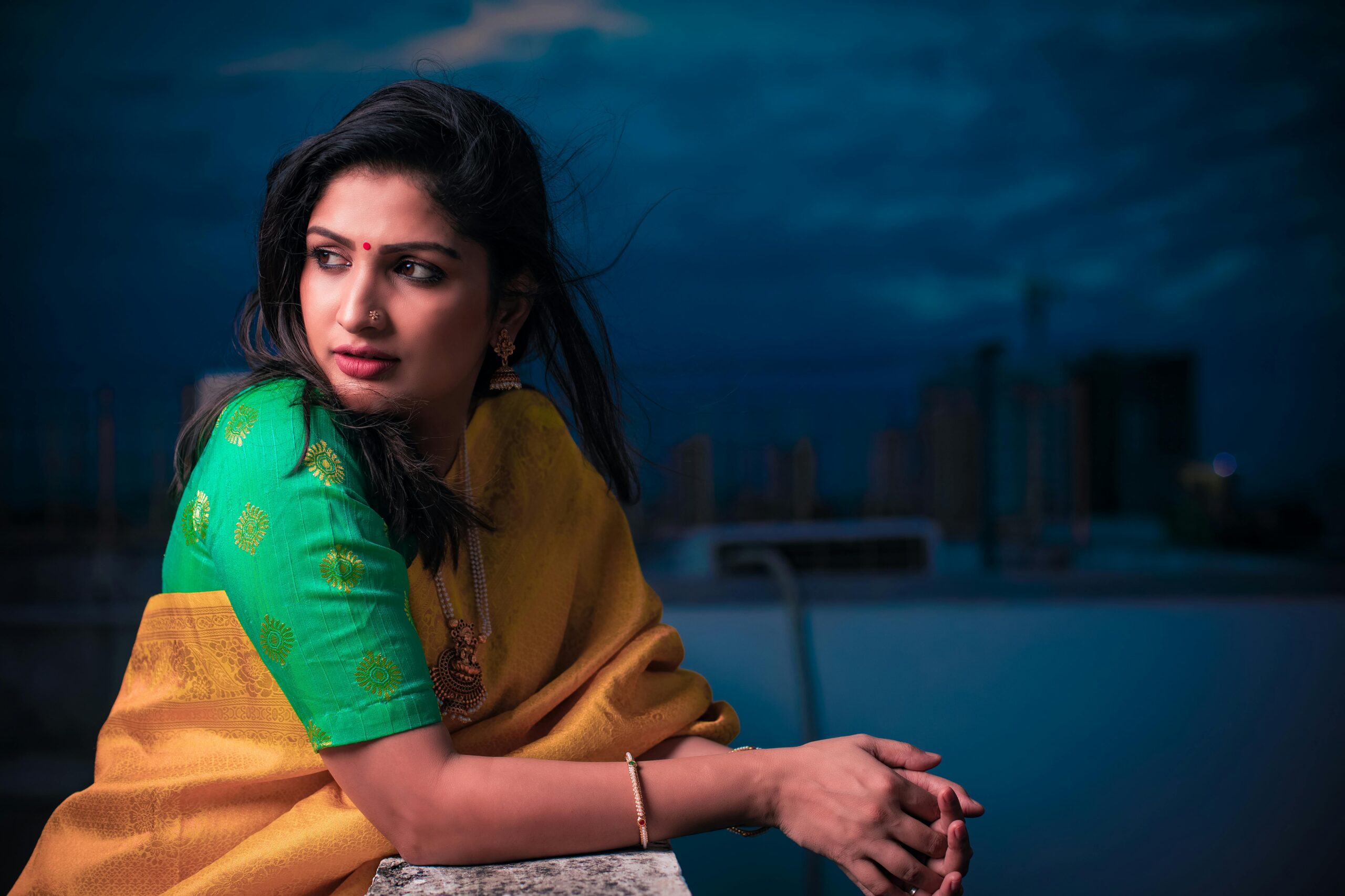 A captivating portrait of a woman in traditional Indian clothing, set against a night city backdrop.